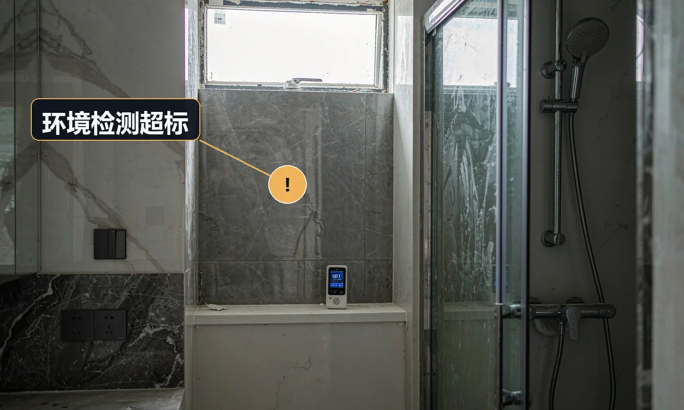 刚装修完的卫生间内,地面台面上放着一台小型空气质量检测仪,屏幕亮着显示数值,旁边是墙砖与淋浴玻璃。